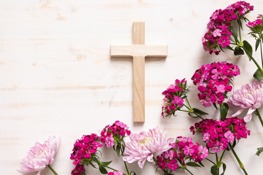 Wood Christian cross with border of pink flwoers on a white wood background with copy space