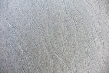 Sand background and texture. Wet beach sand texture after low tide. Sand with wave print. Ripple on the beach sand. 