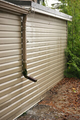 Rain Water Pours Out of a Short Downspout on side of house pooling by foundation