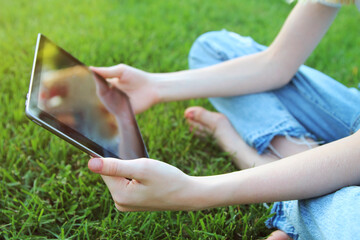 Teen girl  is checking social media holding a tablet outside.