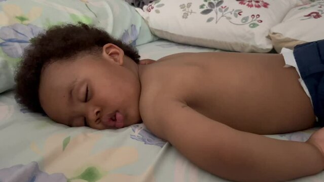 Exotic and cute two year old afro european child sleeping a summer siesta in his bed