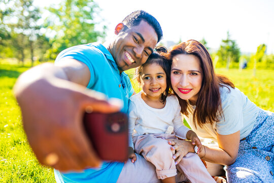 Family with baby on grass in the park authentic emotions taking selfie