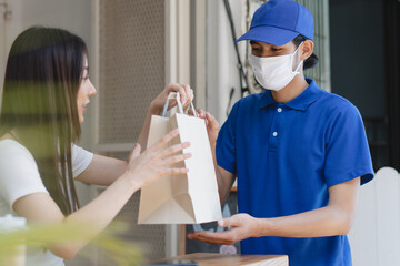 delivery during covid 19 situation. client in protective face mask receiving package from delivery...