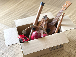 ダンボール箱に入れたたくさんの古い楽器とおもちゃ - obrazy, fototapety, plakaty