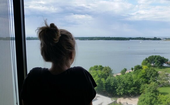 Woman looking out window over Lake Ontario in Toronto, Canada