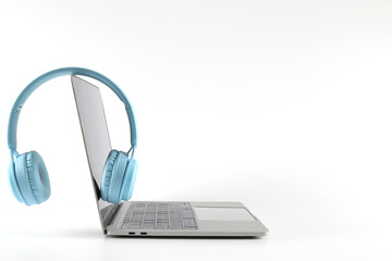 Light blue headphone placed on a laptop isolated on a white background have copy space.