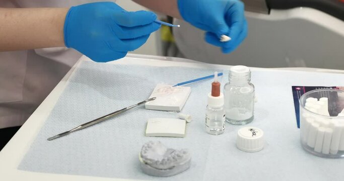 hands of a dentist in medical gloves work with dental implants and crowns in a medical office. Details of dental operation and procedure. medical dental instruments on the medical table . slow motion
