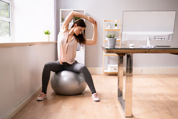 Happy Businesswoman Relaxing On Fitness Ball In Office