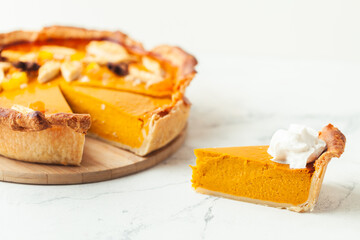 Cut slice of pumpkin pie close up on white background. Autumn orange cake