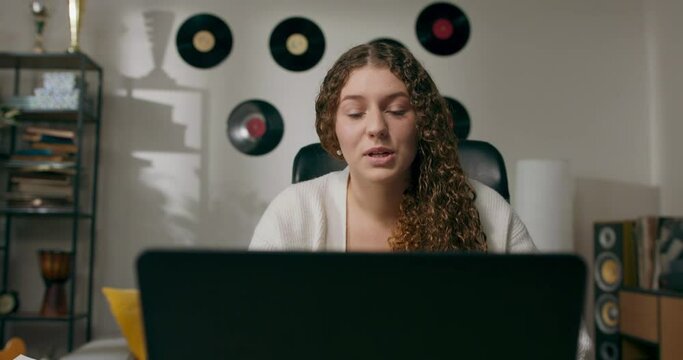 Smiling, beautiful, cheerful girl, staring at the laptop screen, writing notes on the calendar, chatting via video camera with associates,online consultation.