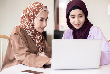 Two Muslim women using laptop for explaining business information in the room