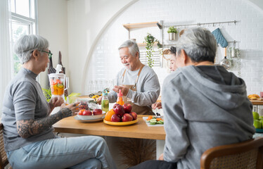 Group of Asian senior people friends making fruit juices for friends to drink in kitchen.colorful fruits and vegetables. Healthy eating