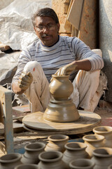 Skilled hands of a potter shaping the clay into pot on spinning wheel