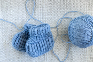 Knitted socks for newborns and ball of thread. Concept of handmade knitted clothes for babies. 