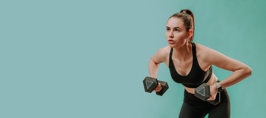 Athletic fitness woman working out with dumbbells on green background. Copy space. - obrazy, fototapety, plakaty