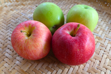 Abtract photo of a group of red and green apples with woven tray background.