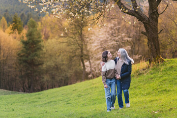 Happy senior grandmother with teenage granddaguhter on walk in nature on spring day.