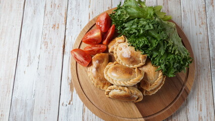 Latin American fried empanadas with tomato sauce. Argentinian Empanada is a pastry turnover filled with a variety of savory ingredients and baked or fried.