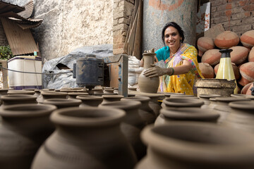 Skilled hands of a female potter shaping the clay into pot on spinning wheel