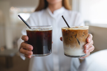 Closeup of a woman holding and serving two glasses of iced coffee