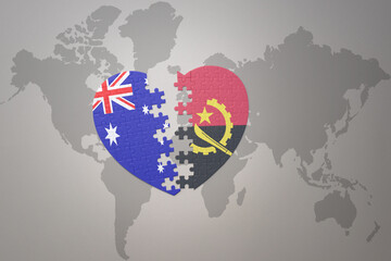 puzzle heart with the national flag of angola and australia on a world map background. Concept.