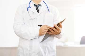 A male doctor in a medical gown writes in the medical history