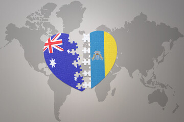 puzzle heart with the national flag of canary islands and australia on a world map background. Concept.