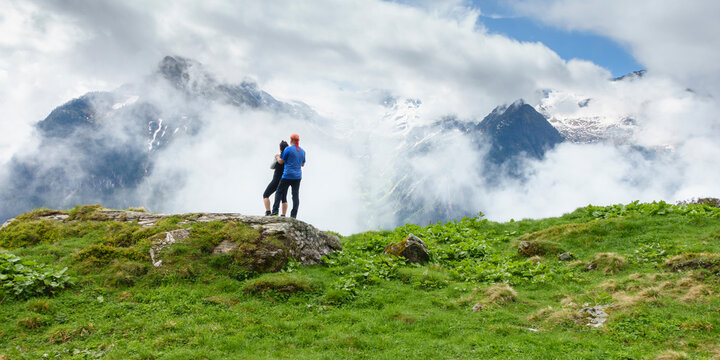 Panoramabild zwei Wanderer schauen in die nebelverhangenen Alpen