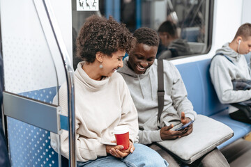 young couple using a smartphone while sitting in a subway car .