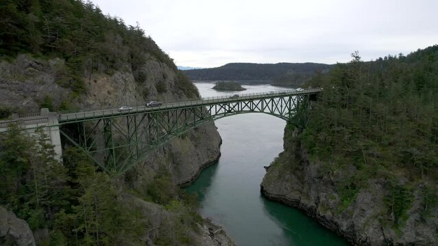Cars driving across arched bridge in Deception Pass along Washington state coast