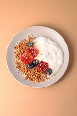 granola bowl decorated with blood oranges, blueberry and coconut. beige background