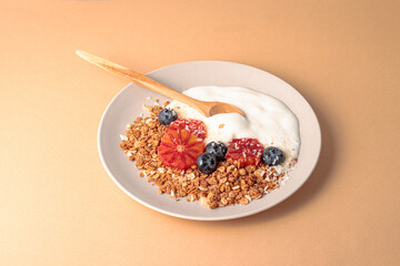granola bowl decorated with blood oranges, blueberry and coconut. beige background