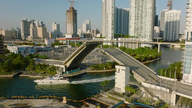 Luxury yacht passing under opened lifting bridge. Scena from tropical city in sunny late afternoon. Miami, USA