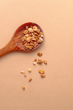 ingredient for breakfast. baked granola with wooden spoone on beige background. close up. top view