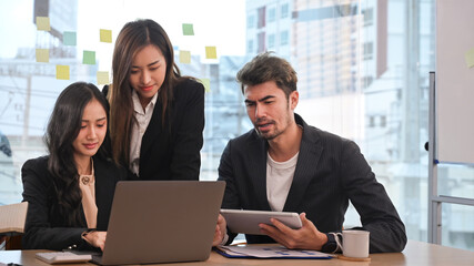 Asian female manager explaining new online project to diverse employees in meeting