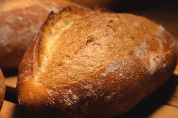 Sourdough bread close-up. Freshly baked round bread with golden crust on bakery shelves. The context of a German bakery with a rustic assortment of bread.