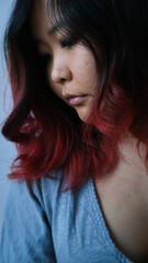 Portrait of a beautiful young asian girl with red hair in a blue dress