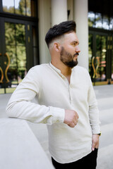 Handsome young guy with a bearded man in a linen shirt on the background of the house