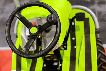 Black steering wheel of neon colored agricultural machinery