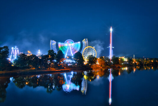 Beleuchtetes Riesenrad auf dem Cannstatter Wasen Fr&uuml;hlingsfest in Stuttgart bei Nacht mit Spiegelung