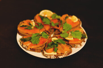 Sandwiches, canape with smoked salmon, butter, herbs on the festive table. Top view food. Black background. Healthy lifestyle, diet