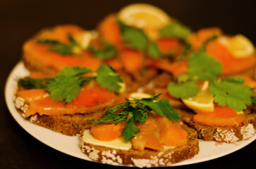 Sandwiches, canape with smoked salmon, butter, herbs on the festive table. Top view food. Black background. Healthy lifestyle, diet