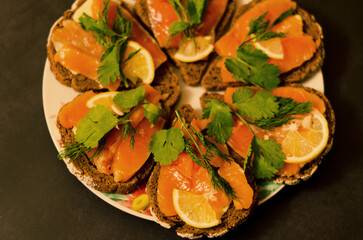 Sandwiches, canape with smoked salmon, butter, herbs on the festive table. Top view food. Black background. Healthy lifestyle, diet