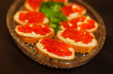 Sandwiches, canape with butter, herbs and red caviar on the festive table. Top view food. Black background