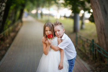 boy gives big red rose to girl. Romantic cute couple of children. Care and hugs, summer photo half-length plan