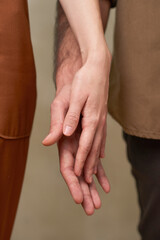 Fototapeta premium Close-up studio shot unrecognizable young man and woman in love standing close to each other touching their hands