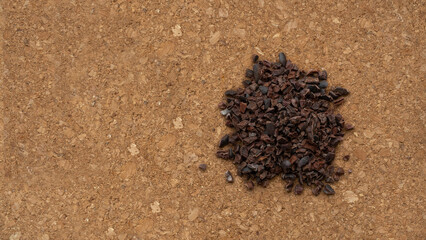 Pieces of cocoa beans lie on a cork background. Coffee, cocoa, chocolate. Organic super food. copy space.