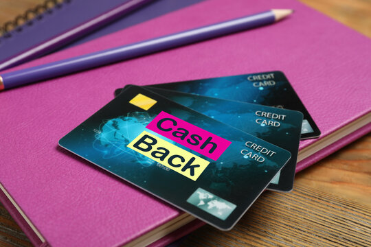 Notebooks, pencils and cashback credit cards on wooden table, closeup