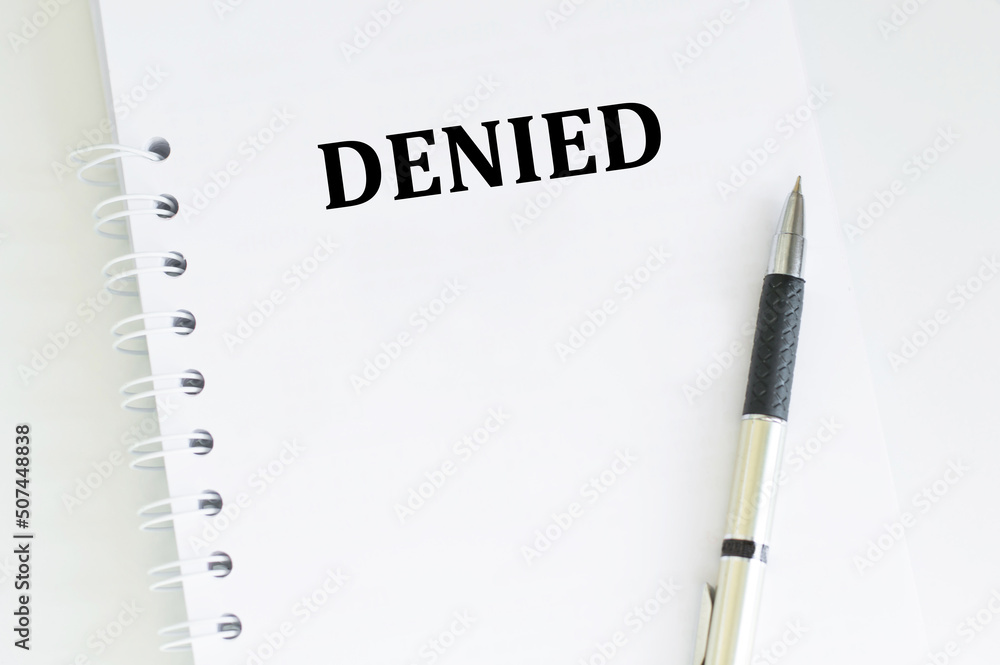 Poster notebook with the text denied on the table next to the pen, business concept