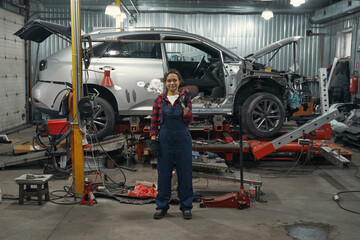 Fototapeta premium Woman auto mechanic standing near vehicle in car garage